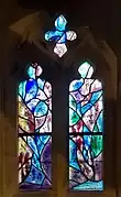 Window 5, warm colours, a blue fish in the quatrefoil