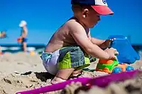 Image 23An infant boy playing with a toy dump truck at the beach. (from Boys' toys and games)