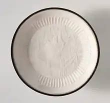 Ding ware dish with garden landscape, "molded stoneware with impressed decoration, transparent glaze, and banded metal rim", 13th century, diameter 5.5 in. (14 cm)