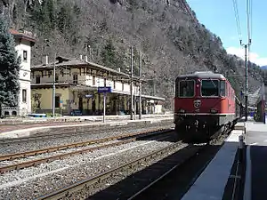Red train in front of yellow two-story building with hip roof