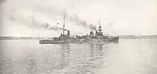 A large light gray ship passes slowly through calm waters.