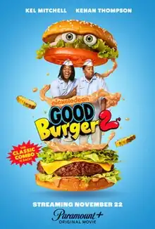 A giant sized buger, with two fast food workers standing in the middle.