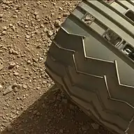 Gravel below one of the 6 wheels on the rover.