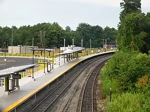 A curved railway platform next to a parking lot