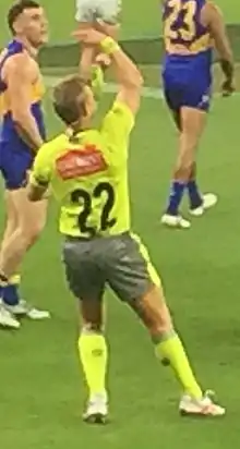 Williamson in fluorescent green umpiring uniform conducting a ball-up