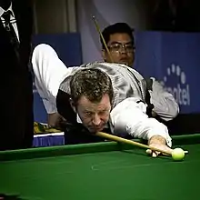 Davis leaning over a table for a shot