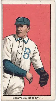 An illustration of a man in a white baseball uniform with a blue "B" on the chest and a blue cap having just thrown a ball.