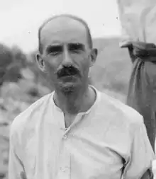 Black-and-white photograph of a middle-aged, moustachioed man, looking directly at the camera.
